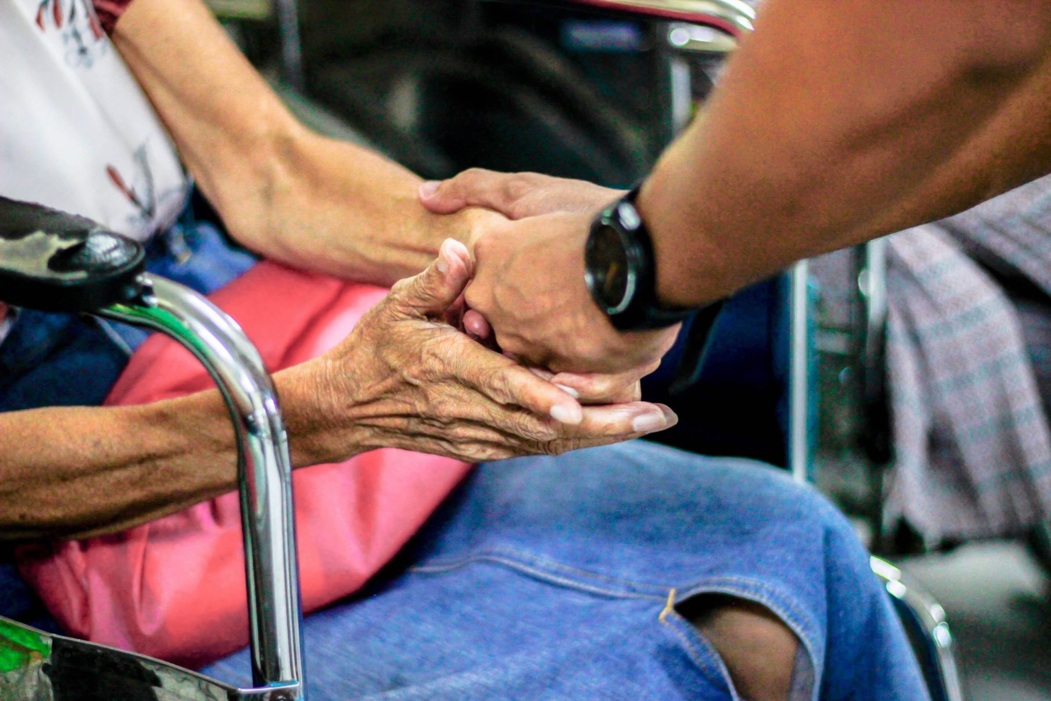 Bild på händer som tar i en äldre persons händer.